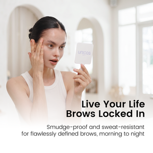 A woman in a white tank top holds a small white square mirror showing the unicos logo while touching her face. The background is a softly blurred indoor setting with arched doorways.