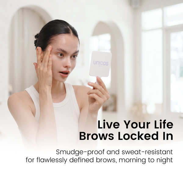 A woman in a white tank top holds a small white square mirror showing the unicos logo while touching her face. The background is a softly blurred indoor setting with arched doorways.