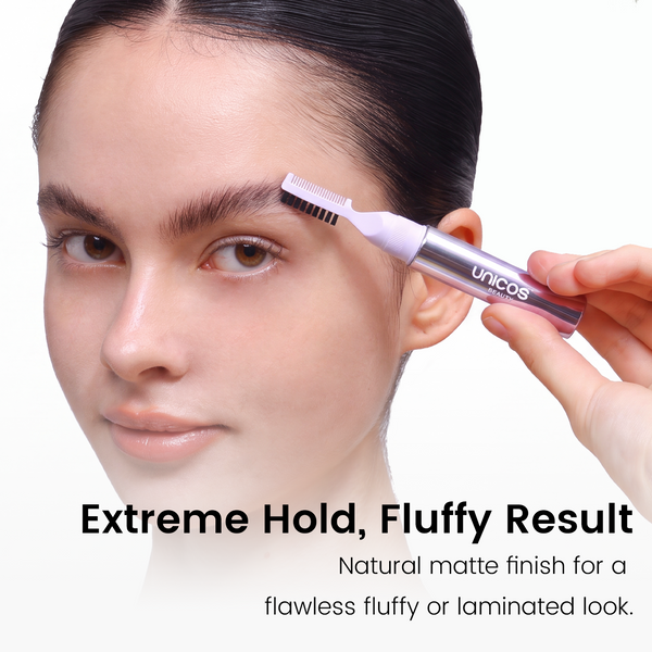 A close-up of a woman's face with a hand holding a unicos eyebrow grooming tool against a white background, with text reading 'Extreme Hold, Fluffy Result'.